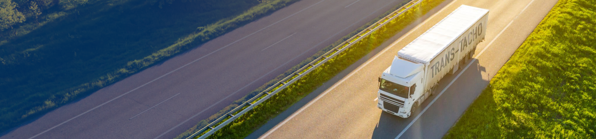 Ciężarówka z logotypem TRANS-TACHO jedzie po autostradzie